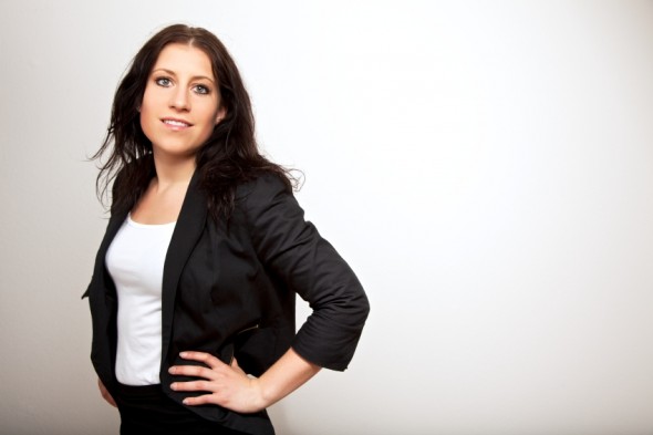 Portrait of a young business executive with hands on hips isolated on gray background