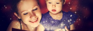 mother and child baby daughter reading magic book in dark