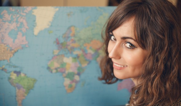 Woman with World Map in Background Looking over Shoulder at Camera as if Planning a Trip