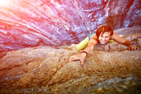 female rock climber climbs on a rocky wall, Keep a hand on the rock and laughs. focus on the hand